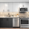 Penthouse kitchen finish with unique pattern backsplash, under-cabinet lighting, and stainless steel appliances such as microwave, oven, dishwasher and fridge.
